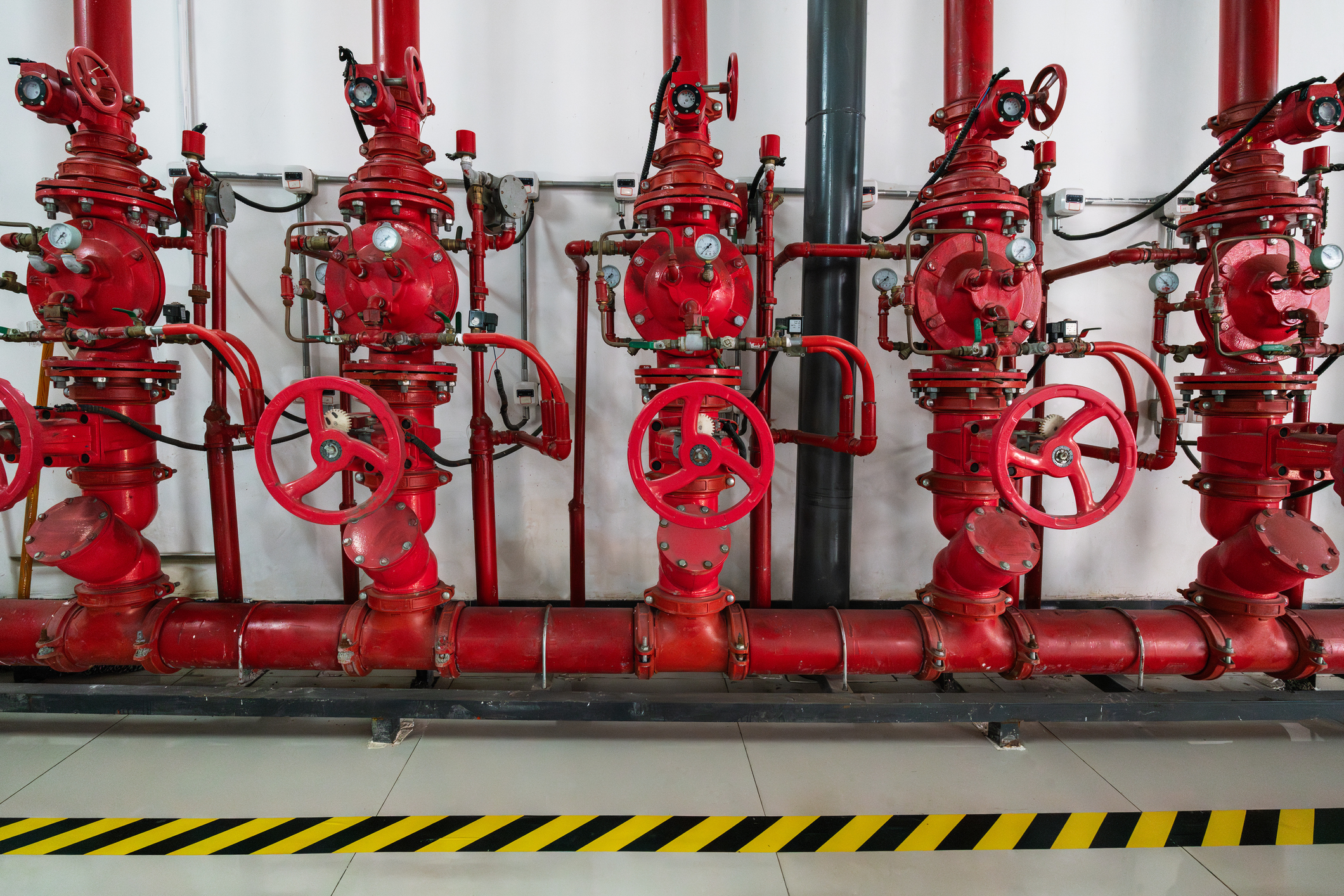Red industrial fire pumps lined up on a wall